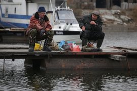 Два рыбака сидят на пирсе с удочками