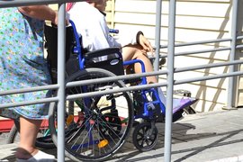 Женщина везет инвалида в коляске по пандусу
