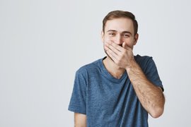 Парень прикрывает рот рукой